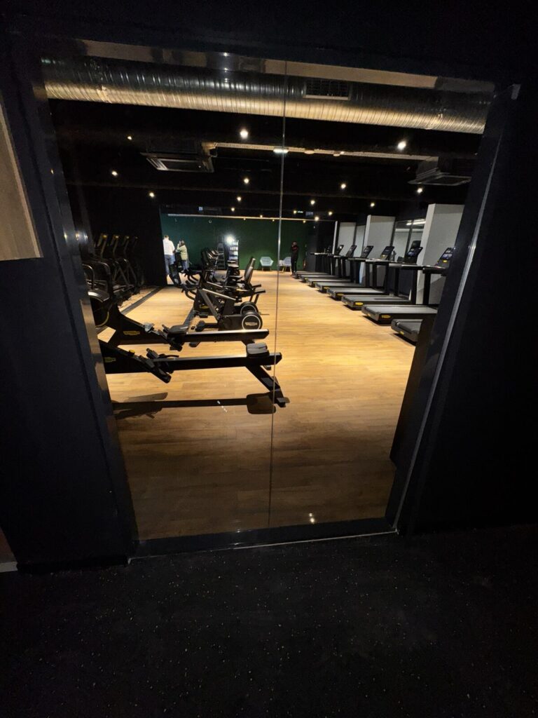 Cloison vitrée posée dans la salle de sport, vue sur les tapis de course