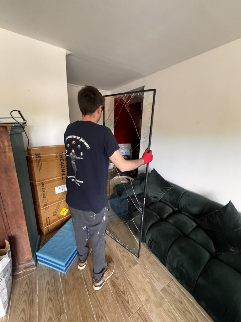 Vitrier retirant le panneau de baie vitrée brisée dans un appartement à Montpellier