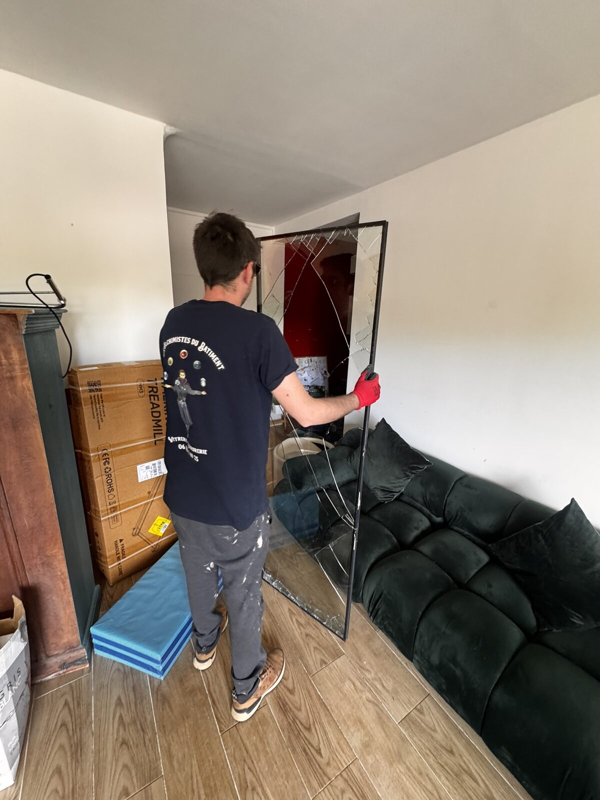 Vitrier retirant le panneau de baie vitrée brisée dans un appartement à Montpellier
