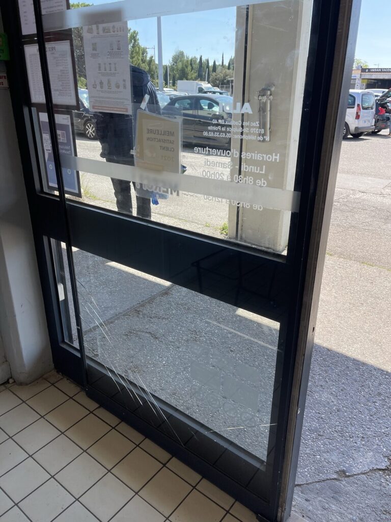 Porte d'entrée de magasin au vitrage éclaté, avant remplacement